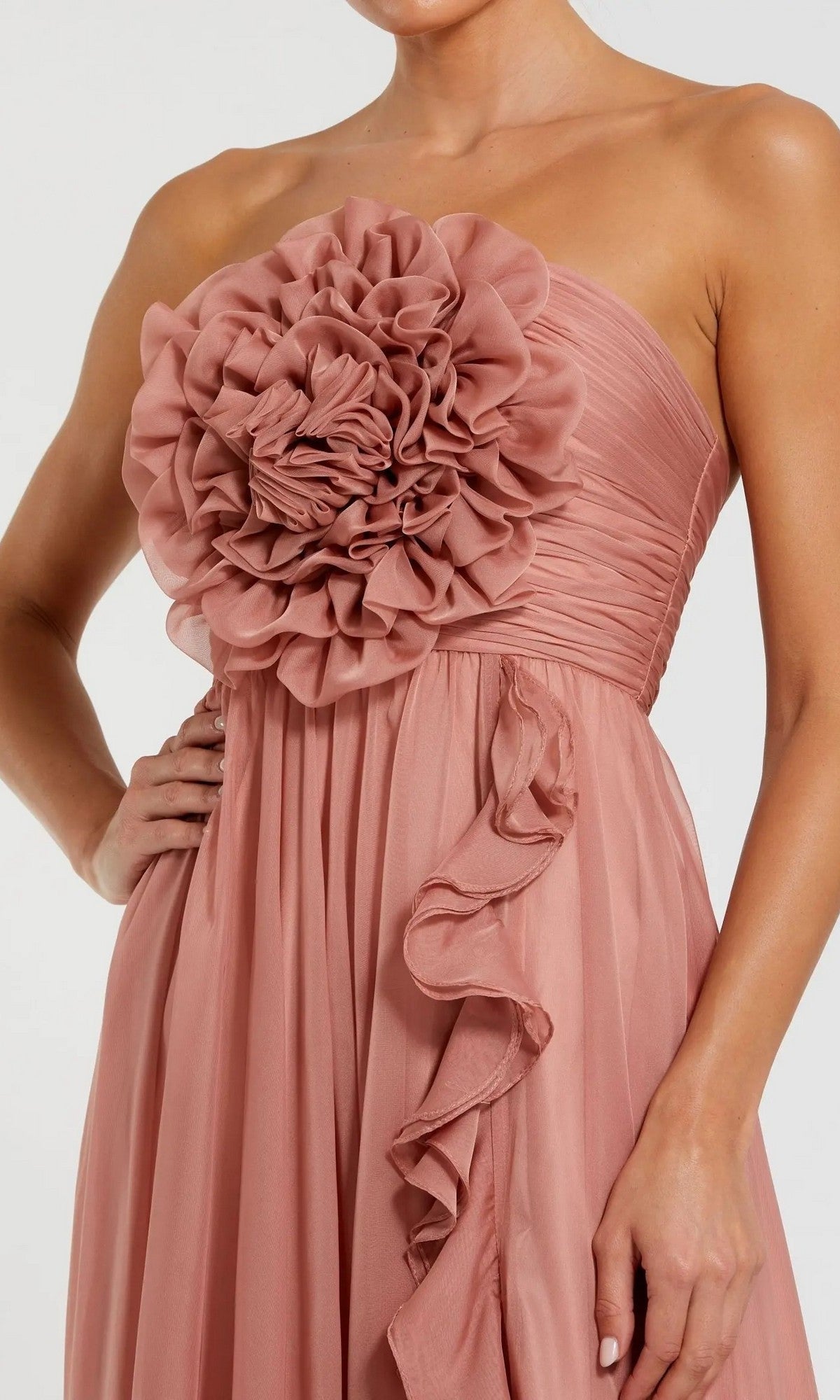 A woman wearing the Mac Duggal 56071 long formal dress, a strapless pink chiffon gown with a dramatic 3D floral bodice and a gathered, flowing skirt in dusty rose.